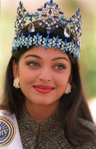 Aishwarya Rai crowned Miss World 1994, wearing a blue jeweled crown and traditional attire, smiling gracefully after her historic win.