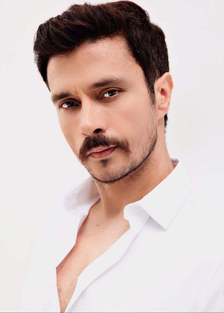 Darshan Kumar with short hair and a trimmed beard wearing a white shirt posing against a plain white background.