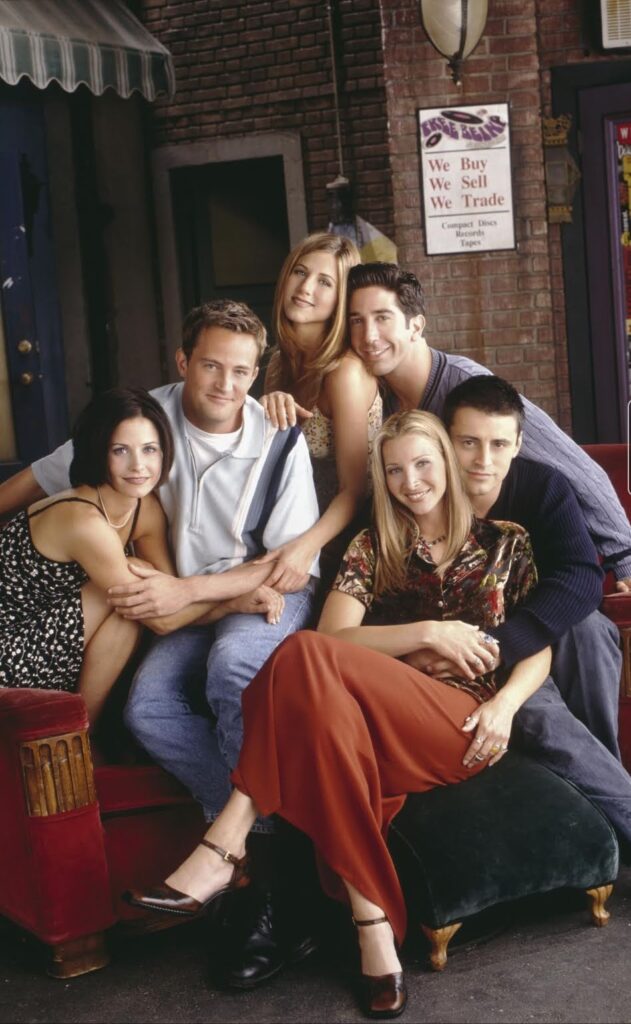 Main cast of Friends sitting closely together on a couch in a promotional photoshoot.